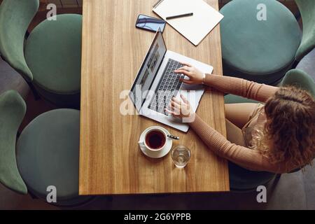 Femme indépendante utilisant un ordinateur portable pour travailler au café Banque D'Images
