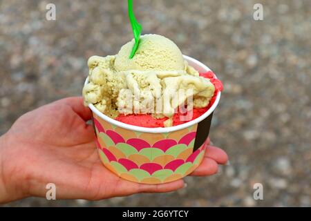 Main tenant une tasse de Takeaway de deux saveurs de crème glacée délicieuse Banque D'Images