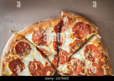 Pizza avec pepperoni hachée en morceaux dans une boîte de courtoisie. Mise au point sélective. Vue de dessus. Banque D'Images