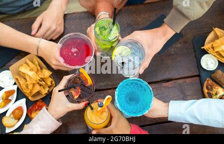 vue rognée sur un groupe de personnes méconnaissables dans un bar-restaurant, où vous pourrez déguster un toast festif avec des cocktails colorés. amis sans visage Banque D'Images