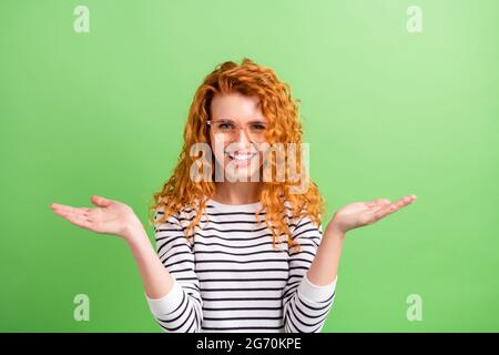 Photo de douce charmante jeune femme porter des lunettes de chemise à rayures montrant les bras pèse-personne espace vide isolé couleur verte arrière-plan Banque D'Images