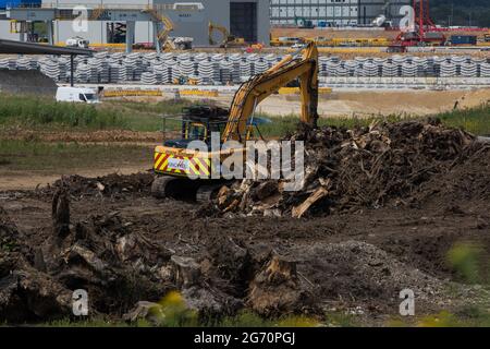 West Hyde, Royaume-Uni. 9 juillet 2021. Une pelle hydraulique déplace les restes d'arbres abattus devant des segments de tunnel conçus avec précision sur le site South Portal pour la section tunnel Chiltern de la liaison ferroviaire haute vitesse HS2. HS2 Ltd a annoncé le lancement de la deuxième foreuse de tunnel (TBM) de 2,000 tonnes, nommée Cecilia d'après l'astronome et astrophysicien Cecilia Payne-Gaposchkin, pour creuser un second tunnel de 10 milles sous les Chilterns. Crédit : Mark Kerrison/Alamy Live News Banque D'Images