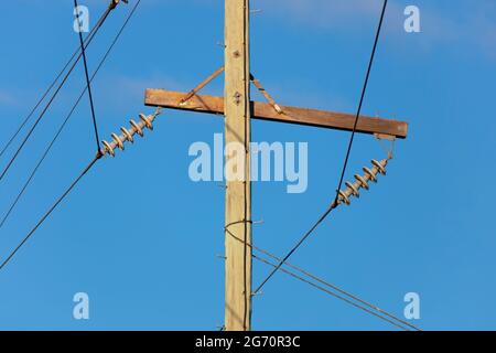 Photographie d'un poste téléphonique en bois et de câbles contre un ciel bleu Banque D'Images