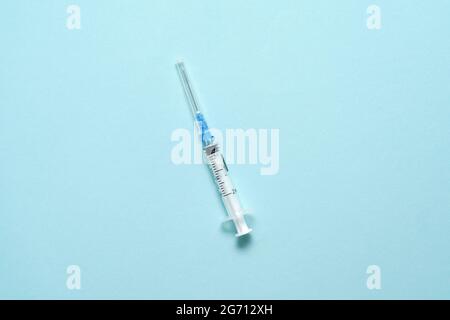 Vue de dessus de la seringue d'injection sur fond bleu. Concept de vaccin minimal. Traitement médical du diabète avec l'insuline. Vaccination Covid-19. Antivax Banque D'Images