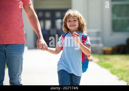 Père et fils américains marchant dans le parc scolaire. Première journée à l'école. Le père dirige une petite fille d'école d'enfant en première année. Banque D'Images