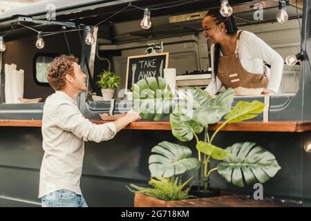 Chef africain femme prenant la commande du client à camion de nourriture en plein air - Focus sur le visage de l'homme Banque D'Images