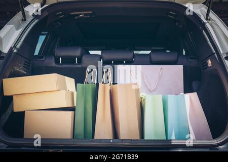 Sacs à provisions entièrement en papier et fourre-tout dans le chariot. Sac coloré et boîte marron dans le coffre de rangement arrière de voiture. Addiction shopping ou concept shopping. Banque D'Images