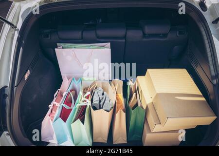 Sacs à provisions entièrement en papier et fourre-tout dans le chariot. Sac coloré et boîte marron dans le coffre de rangement arrière de voiture. Addiction shopping ou concept shopping. Banque D'Images