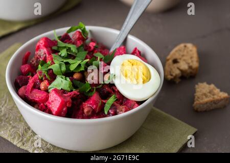 Vinaigrette russe à salade dans des assiettes avec œufs durs et pain noir, salade de légumes durs et marinés et pois verts en conserve Banque D'Images