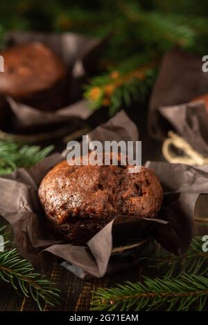 Délicieux muffins au chocolat sur fond de bois sombre parmi les branches de sapin, Joyeux Noël et bonne année Banque D'Images