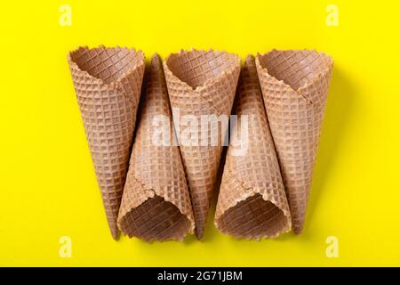 Cornets de glace à gaufrer vides sur fond jaune, à plat Banque D'Images