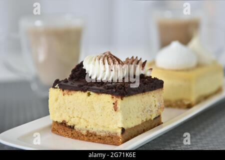 Cliché sélectif de deux morceaux de gâteau et de tasses de café dans un café Banque D'Images
