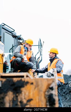 Contremaître montrant le travailleur dans la direction de la fosse minière à ciel ouvert avec ARM étiré Banque D'Images