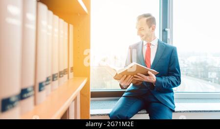 Procureur de droit dans la bibliothèque de son bureau de lecture et de réflexion sur une stratégie Banque D'Images