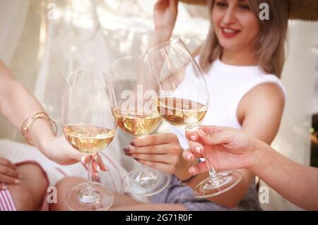 Par dessus les amies anonymes se clinquant des verres de vin tout en étant assis sur des couvertures près des assiettes avec des fruits pendant le pique-nique Banque D'Images