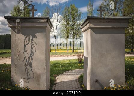 portes de l'église avec deux croix catholiques. Champ de pissenlits avec quelques arbres en arrière-plan. Ombres de fils sur les colonnes, jour de printemps ensoleillé, conrete brique pa Banque D'Images