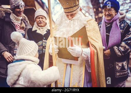 Saint Nicolas lisant des histoires de la Bible à un enfant Banque D'Images