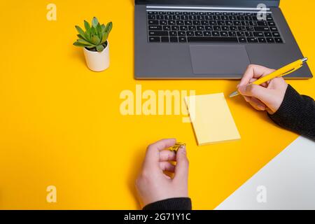 Femme main tenant des notes vierges écrire de nouvelles mises à jour de Messege idées à côté de l'ordinateur portable. Lady Palm montrant enveloppe pliage envoi de lettres adresse postale et Banque D'Images