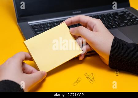 Femme main tenant des notes vierges écrire de nouvelles mises à jour de Messege idées à côté de l'ordinateur portable. Lady Palm montrant enveloppe pliage envoi de lettres adresse postale et Banque D'Images