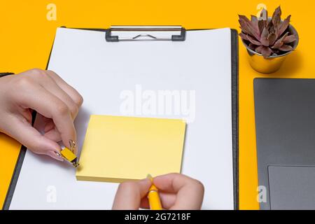 Femme main tenant des notes vierges écrire de nouvelles mises à jour de Messege idées à côté de l'ordinateur portable. Lady Palm montrant enveloppe pliage envoi de lettres adresse postale et Banque D'Images