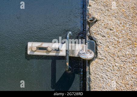 Cadenas en acier inoxydable sur une porte en métal peinte en vert brillant avec poignée en position verrouillée. Banque D'Images