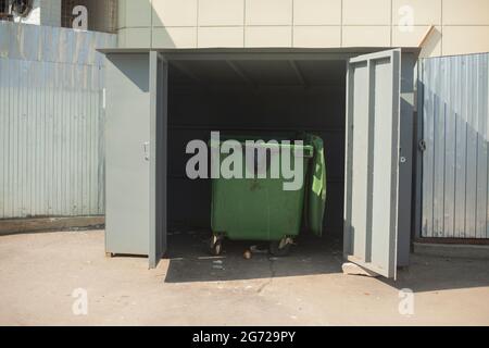 Poubelle. Conteneur de déchets dans une zone clôturée. Collecte des déchets du magasin. Élimination des déchets. Conteneur en plastique sur roues. Banque D'Images