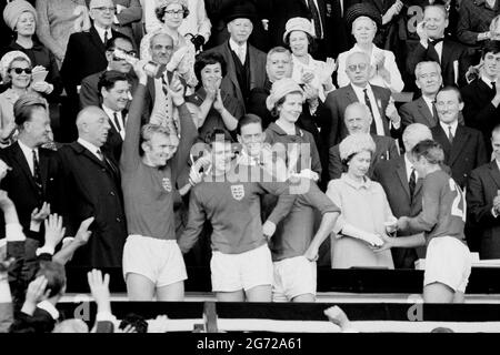 EMBARHOED À 1830 SAMEDI JUILLET 10 photo du dossier datée du 30/07/66 du capitaine d'Angleterre Bobby Moore tenant le Trophée Jules Rimet, suivi de Geoff Hurst, Bobby Charlton et Roger Hunt, recevant sa médaille de la reine Elizabeth II, après avoir battu l'Allemagne de l'Ouest en finale de la coupe du monde à Wembley, Londres. La Reine a envoyé une lettre au responsable du football d'Angleterre Gareth Southgate pour le féliciter ainsi qu'à l'équipe de football d'avoir atteint la finale de l'UEFA Euro 2020 et lui envoyer de bons voeux avec « l'espoir que l'histoire enregistrera non seulement votre succès, mais aussi l'esprit, l'engagement et la fierté avec lesquels vous êtes Banque D'Images