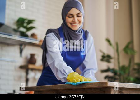 Portrait d'une femme musulmane souriante qui nettoie une maison Banque D'Images