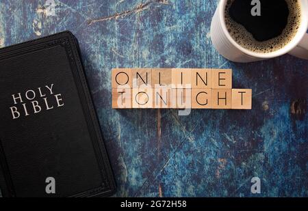 En ligne ce soir écrit en bloc lettres sur une table en bois bleu avec une Bible noire Banque D'Images