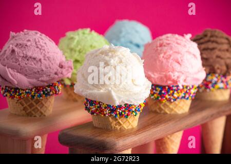 Six différentes saveurs de crème glacée en Cones de sucre sur fond rose vif Banque D'Images