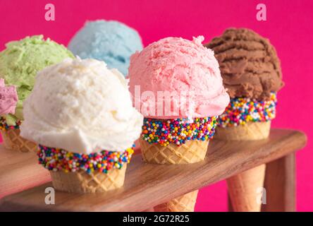 Six différentes saveurs de crème glacée en Cones de sucre sur fond rose vif Banque D'Images