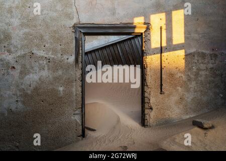 Bâtiment abandonné en train d'être repris par l'empiétement du sable, ville fantôme de Kolmanskop, désert du Namib, Namibie. Banque D'Images