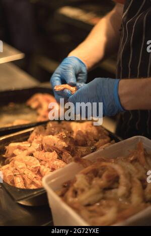 chef épluchant les crevettes avec des gants bleus Banque D'Images