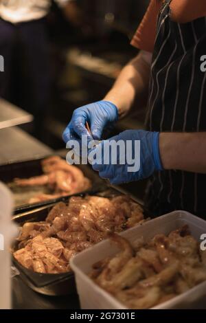 chef épluchant les crevettes avec des gants bleus Banque D'Images