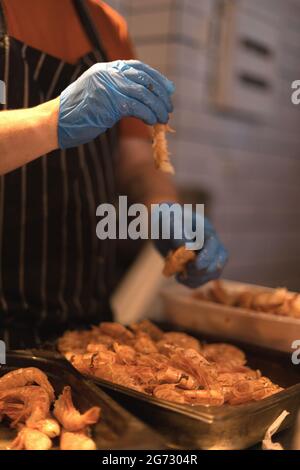 chef épluchant les crevettes avec des gants bleus Banque D'Images