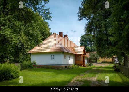 Vieux bâtiments de ferme et une cour entourée d'arbres dans un paysage de campagne lors d'une belle journée ensoleillée de dummer. Zwierzyniec, Roztocze, Pologne. Banque D'Images