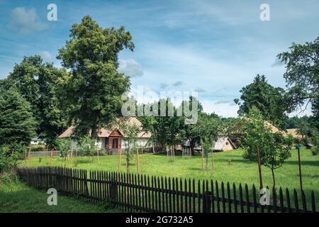 Vieux bâtiments de ferme et une cour entourée d'arbres dans un paysage de campagne lors d'une belle journée ensoleillée de dummer. Zwierzyniec, Roztocze, Pologne. Banque D'Images