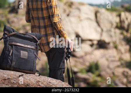 Jeune adulte en chemise avec sac à dos gris tenant une binoculaire pour regarder autour ou observer les oiseaux. Concept de voyage Banque D'Images