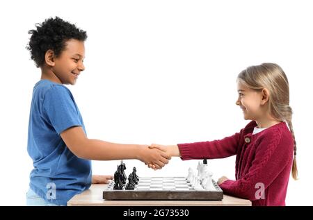 Petits enfants adorables jouant aux échecs sur fond blanc Banque D'Images