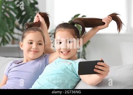 De jolies filles jumelles emportant un selfie à la maison Banque D'Images