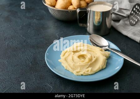 Assiette avec une purée de pommes de terre savoureuse et des ingrédients sur fond sombre Banque D'Images