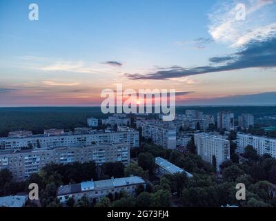 Vue aérienne du lever du soleil le matin sur le quartier résidentiel de Kharkiv Pavlove Pole. Bâtiments à plusieurs étages avec ciel nuageux pittoresque et soleil orange à l'horizon Banque D'Images