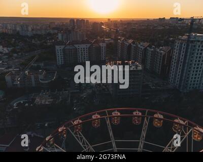 Vue sur le coucher du soleil sur la grande roue aérienne dans le centre-ville de Kharkiv, parc d'attractions de Maxim Gorky dans la zone résidentielle de bâtiments à plusieurs étages. Haute attraction f Banque D'Images