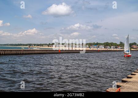 South Haven, MI, États-Unis - 7 juin 2008 : deux jetées forment un canal à la sortie de Black River dans le lac Michigan sous un paysage bleu clair. Voile yacht sur Dark wa Banque D'Images