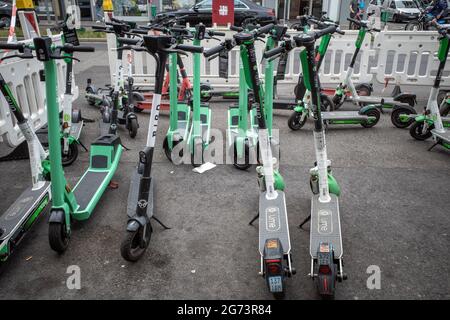 Rangée de trottinettes électroniques par diverses compagnies, avec Eco friendly Mobility concept de partage Electric Scooter, parc sur le trottoir devant le style européen. Banque D'Images