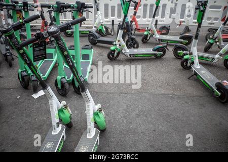 Rangée de trottinettes électroniques par diverses compagnies, avec Eco friendly Mobility concept de partage Electric Scooter, parc sur le trottoir devant le style européen. Banque D'Images