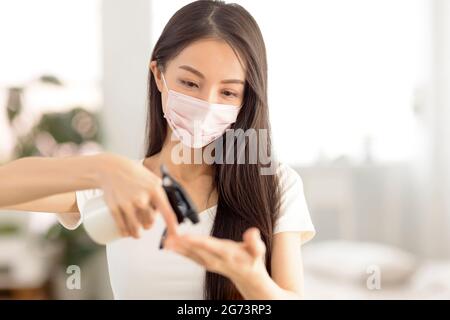 Jeune femme portant un masque de sécurité et utilisant un spray de désinfection Banque D'Images