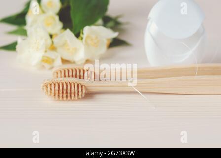 Deux brosses à dents en bambou, fil dentaire et fleurs blanches, gros plan Banque D'Images