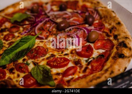 Une délicieuse pizza croustillante avec des saucisses et du basilic frais Banque D'Images