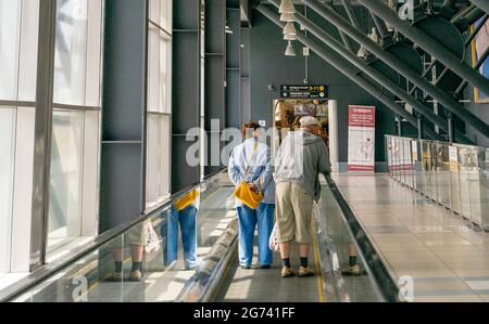 Couple âgé, homme avec bâton de marche et femme, sur la passerelle mobile dans l'aéroport, vue arrière, Tolmachevo, Novosibirsk, Russie Banque D'Images